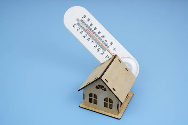 istock Wooden house model and thermometer on blue background. 2195634699