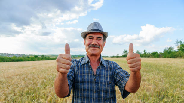 istock Elderly farmer man with mustache shows thumb up, looking at camera. 2195636534