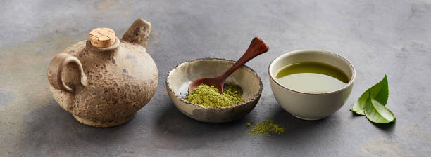 istock Green matcha powder with leaves and clay tea pot on graphite background 2195639414