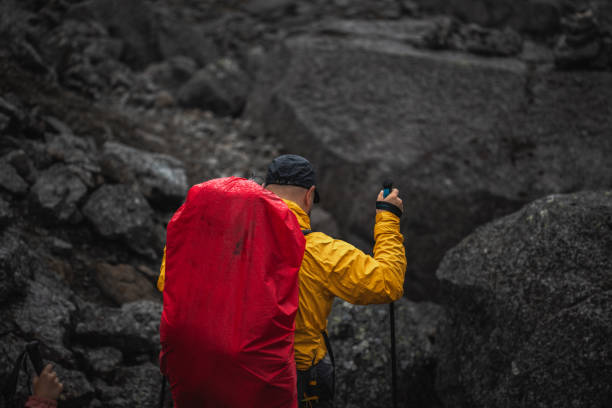 Woman with backpack and hiking poles got to the top of Africa - Mount Kilimanjaro and looking at the beautiful bright sunny sunrise above the Meru mountain