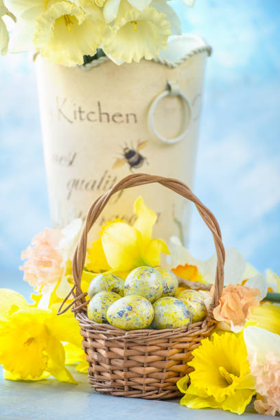 Chocolate mini Easter eggs in green straw on a whicker basket against a white background