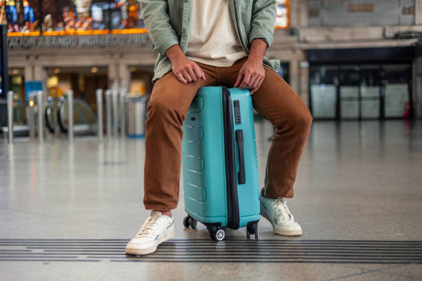 istock Tourist sitting on suitcase waiting for train at station 2195642994
