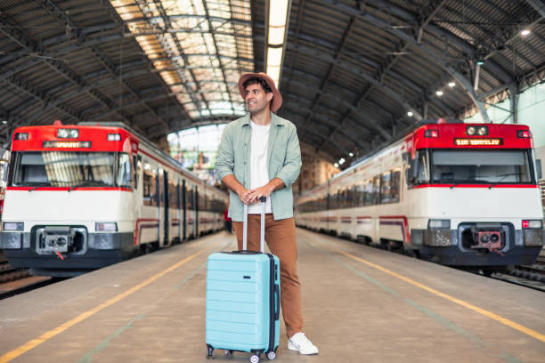 istock Tourist waiting for train at station with suitcase 2195643141