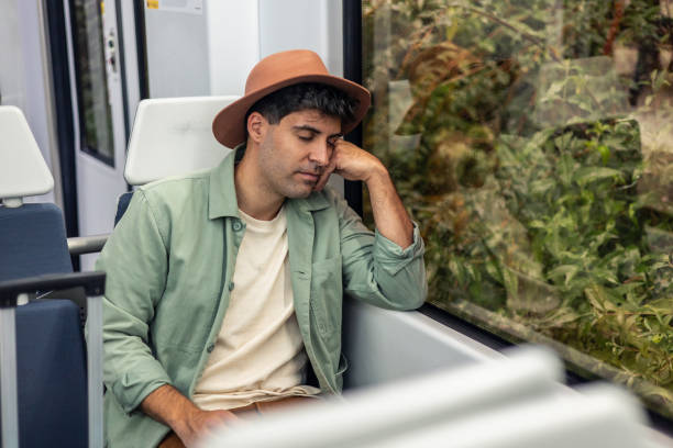 Young tourist wearing a hat sleeping peacefully on a train by the window, savoring a moment of relaxation during a vacation journey filled with comfort and adventure