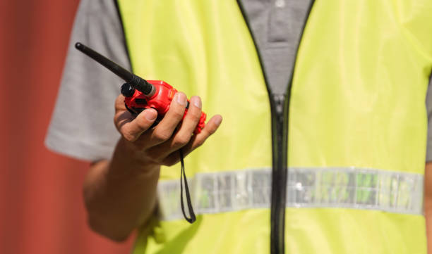 Construction manager holding a red walkie-talkie for communication in a safety vest