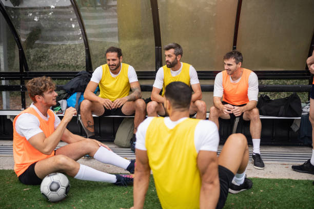 A group of young men gets ready for soccer practice on a vibrant sports field in Sydney. They are changing into their jerseys, displaying enthusiasm for the upcoming training session.