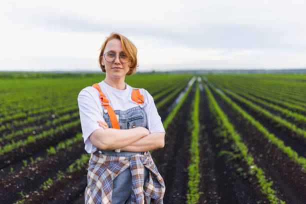 A farmer wearing casual attire stands confidently in a green agricultural field. This image represents sustainable farming, dedication, and the hard-working spirit required for successful crop production.