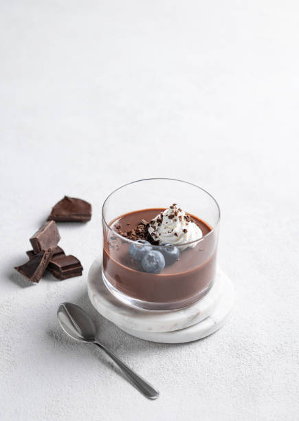 istock Chocolate pudding in a glass with whipped cream and fresh blueberry on a light background 2195649622