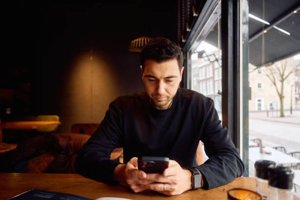 istock Young adult man using smartphone in a restaurant 2195653253