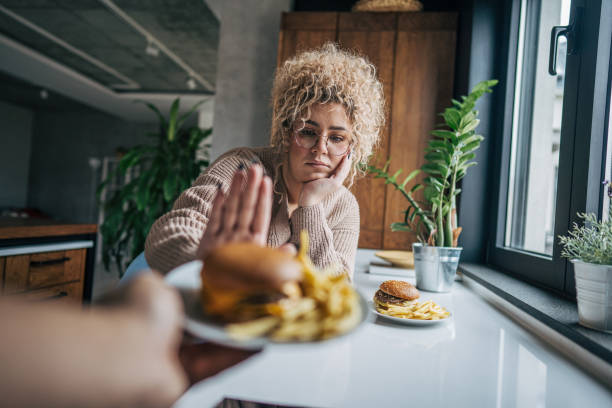 istock A chubby woman refuses to take a burger 2195659559