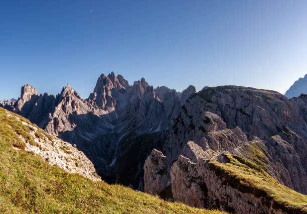 Sharp Mountain Peaks and Grass-Covered Slopes in the Dolomites with Morning Light.