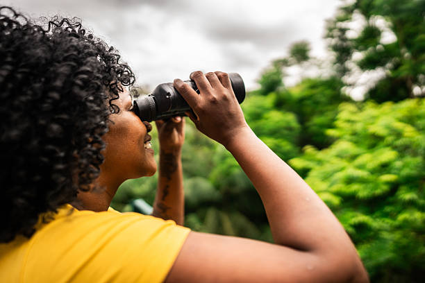 istock Mid adult tourist woman using binoculars at forest 2195663174