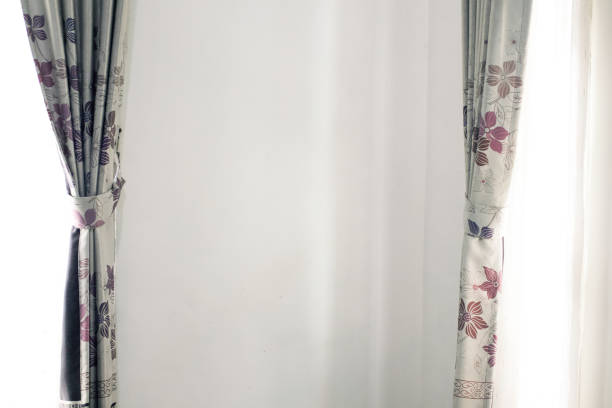 istock Patterned curtains hang on either side of a white wall allowing natural light to filter through 2195663225