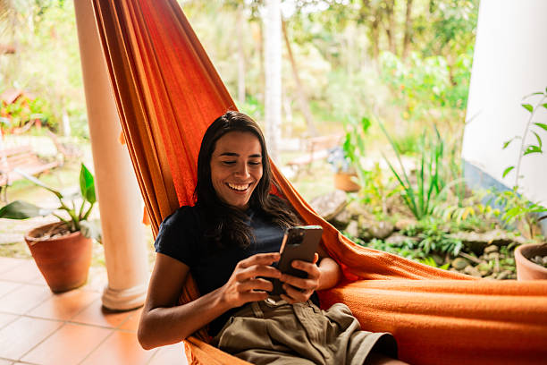 istock Young woman using mobile phone on hammock outdoors 2195663365