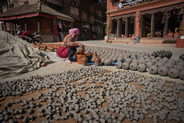 A Nepalese woman coloring a piggy bank clay pot for being sun-dried at Pottery Square, Bhaktapur, Nepal.
