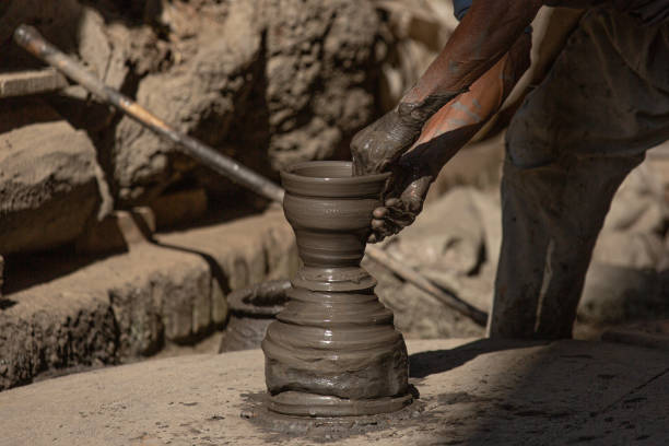 An old man is making a Piggy Bank clay pot in his workshop at Pottery Square, Bhaktapur, Nepal. Nepalese Potter works in their small-scale traditional pottery-making industry in Bhaktapur, Nepal. Bhaktapur is an ancient town in the Kathmandu Valley and is listed as a World Heritage Site by UNESCO for its rich culture, temples, and wood, metal, and stone artwork.