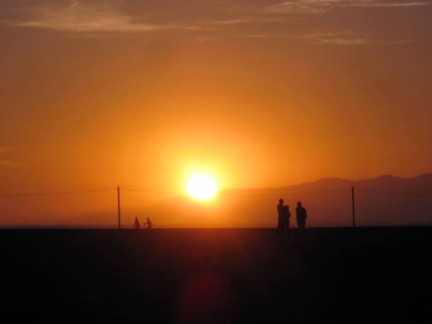People walk down the beach in Los Angeles as the sun sets.
