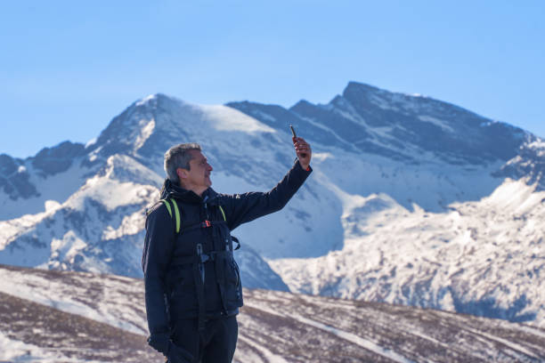 istock Man Taking Selfie with Snowy Mountain Peaks 2195665895