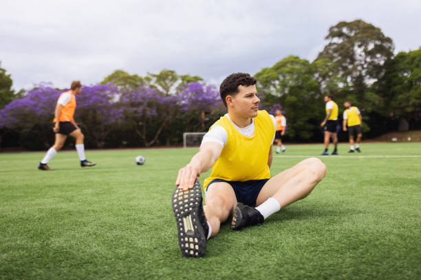 istock Soccer Player Stretching During Team Warm-Up on the Field 2195668448