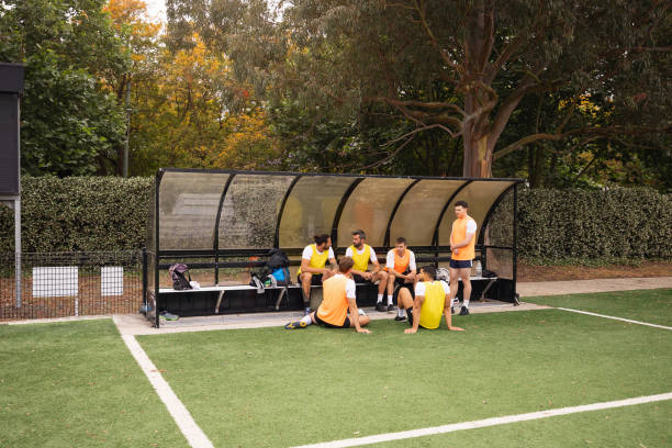 istock Football Team Resting on Bench During Practice in Outdoor Stadium 2195668794