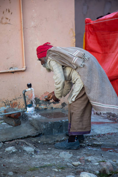 istock Senior Indian man drinking water from a public faucet in Rishikesh 2195670122