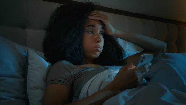 African American girl scrolling smartphone mobile phone online apps in bed before sleeping upset shocked ethnic woman customer worried internet problem loss connection error mistake bad news rejection. High quality 4k footage