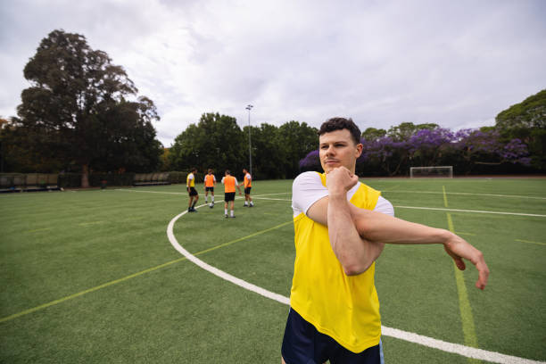 istock Football Player Stretching Before Team Practice on Outdoor Field 2195670839