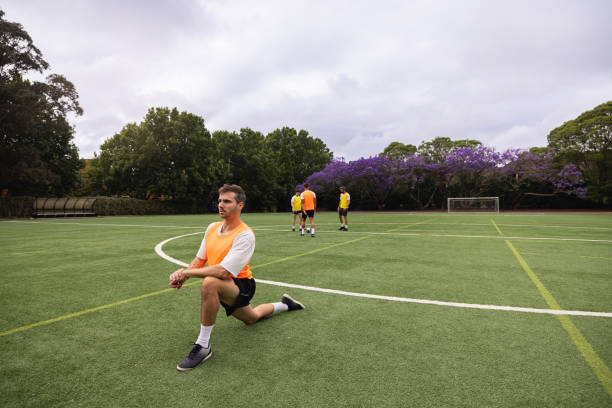 istock Soccer Player Stretching Legs on Field During Outdoor Training Session 2195671119