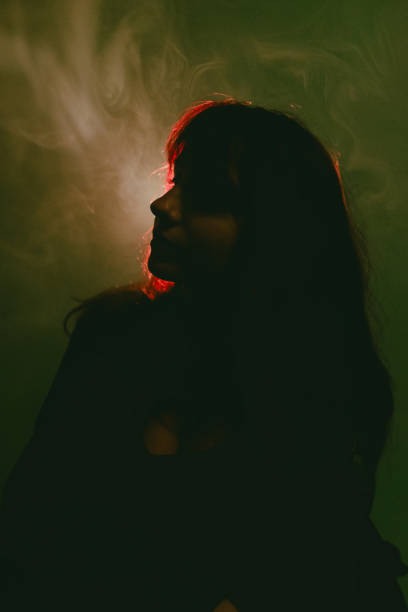 istock Woman breathing smoke in atmospheric lighting 2195675137