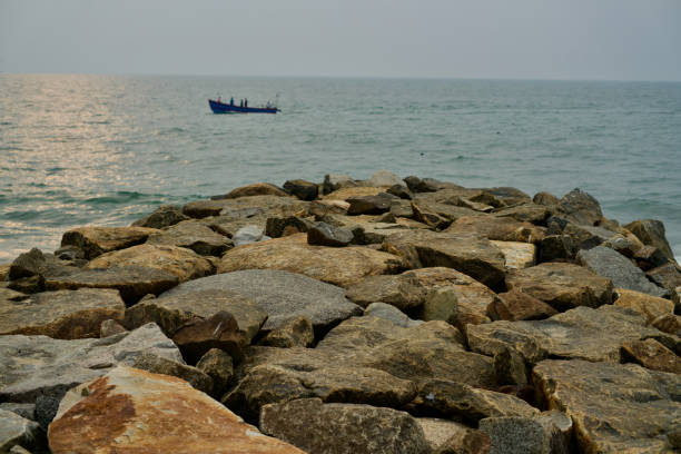 View of rocky breakwater and fishing boat in the sea
