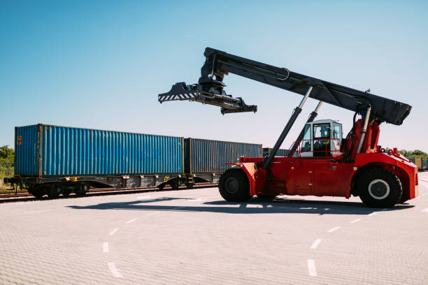 istock Industrial Reach Stacker Near Blue Shipping Container on a Sunny Day 2195678862