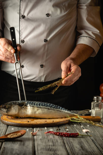 istock A skilled chef skillfully seasons a whole fish with aromatic herbs, surrounded by rustic kitchen tools. The warm ambiance enhances the culinary artistry in this vibrant scene 2195681263