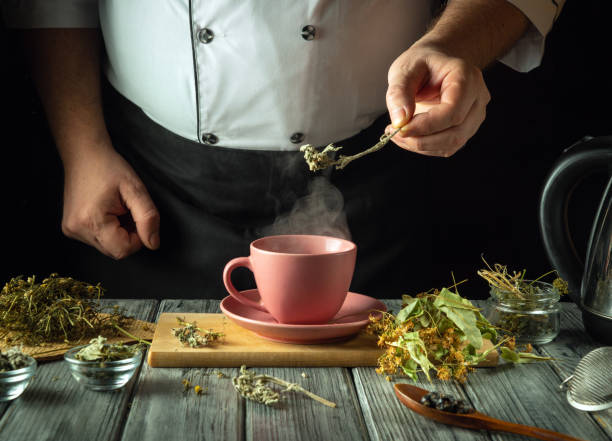 istock Herbalist prepares fragrant tea on the kitchen table. Using her hands, add motherwort to a pink mug of boiling water to make a soothing tea. Traditional medicine concept or making a medicinal tea 2195681450