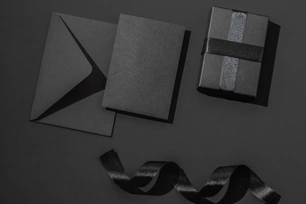istock Black gift box with satin ribbons and a black envelope on a black background. Greeting card. 2195682387