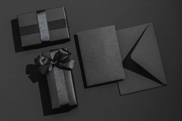 istock Two black gift box with satin ribbons and a black envelope on a black background with space for text. Greeting card. 2195682403