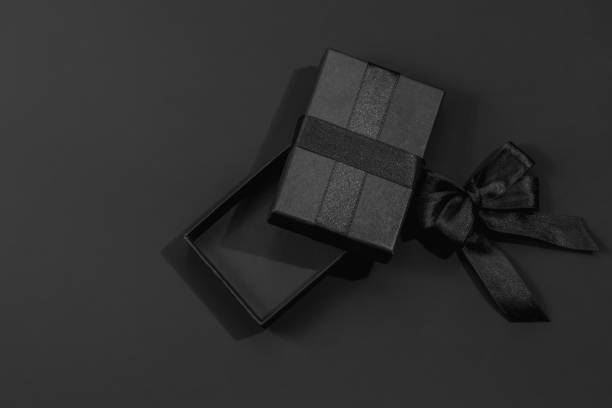 istock Opened black gift box and satin ribbon with bow on dark black background with space for text. Gifts for him, happy father's day. 2195682408