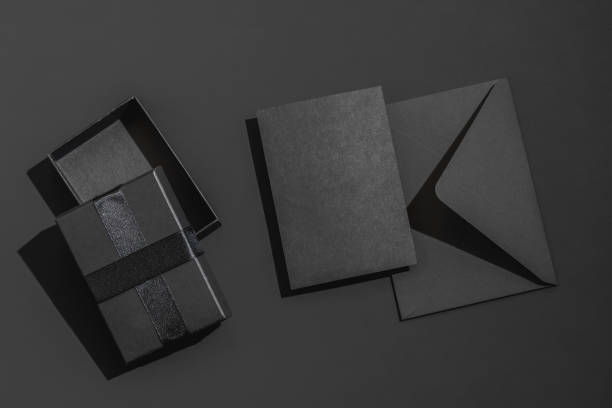 istock Blank black gift box with satin ribbon and black envelope on a black background with space for text. 2195682409