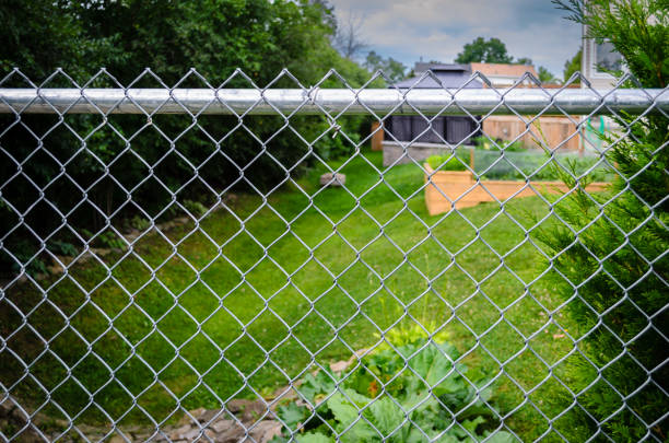 Suburban backyard decks and garden behind a chain-link fence Suburban backyard decks, gazebo and garden behind a chain-link fence on a sunny morning wood and wire fence designs pictures stock pictures, royalty-free photos & images