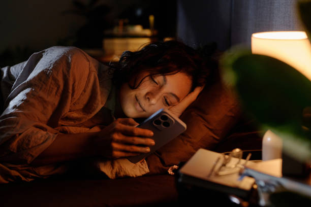 istock Smiling Woman Checking Social Network before Bed 2195686975
