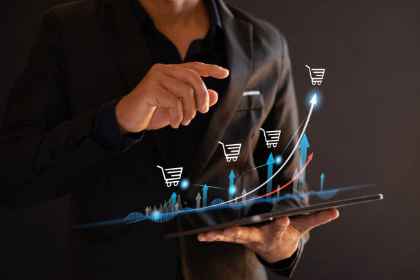 istock Sales growth. Merchants hold charts displaying sales growth, with shopping carts and e-commerce business growth percentages displayed on the screen. 2195692642