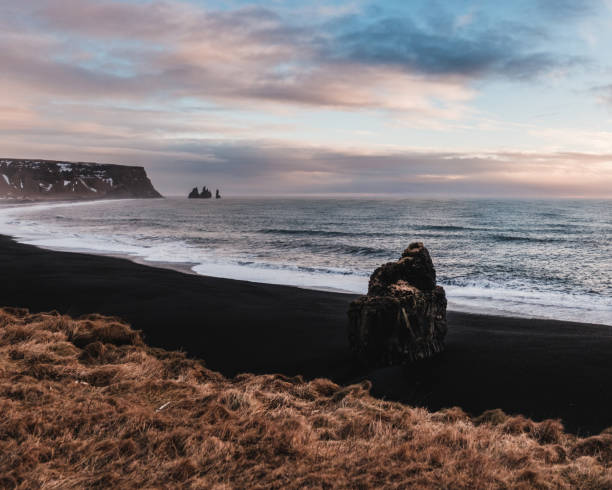 istock Arnardrangur sea stack and Reynisdrangar basalt columns on the black sand beach, South Iceland. 2195694203