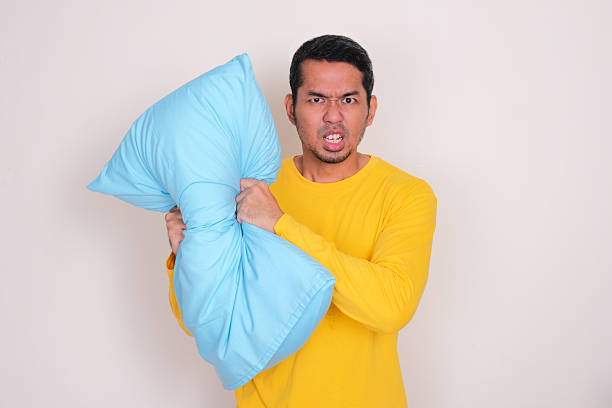 istock Adult Asian man crushing a pillow showing angry expression 2195699775