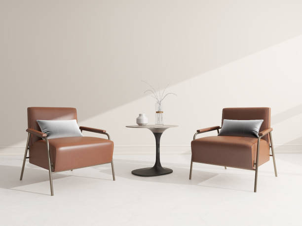 istock A modern minimalist interior design featuring two brown leather armchairs with metal frames, a small round side table with a vase and decorative branches, set against a light beige wall. 2195700951