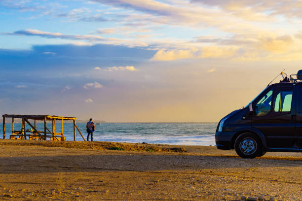 Camper van recreational vehicle at sunrise on mediterranean coast in Spain. Camping on beach. Vacation and traveling in motor home.