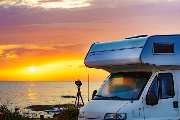 istock Camper and camera on tripod on beach at sunrise 2195706781