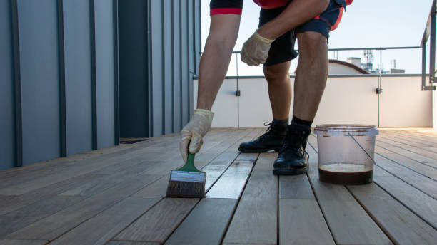 istock Worker applying wood finish to deck on rooftop during daytime 2195711701