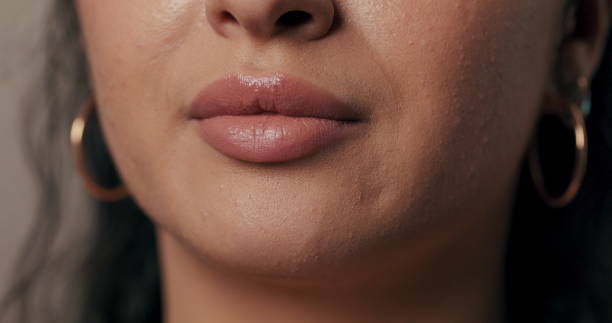 istock Pretty model standing against a plain beige backdrop, wearing simple nude makeup close up on glowy lips 2195714170