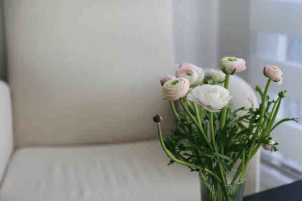 Bouquet of ranunculus flowers near empty beige armchair Close up, copy space, background.