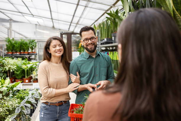 istock Florist Guiding Young Couple in Selecting Potted Plants 2195718407
