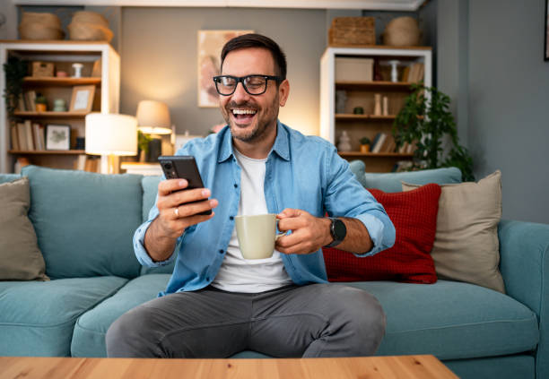 istock Young cheerful man using phone at home 2195719141